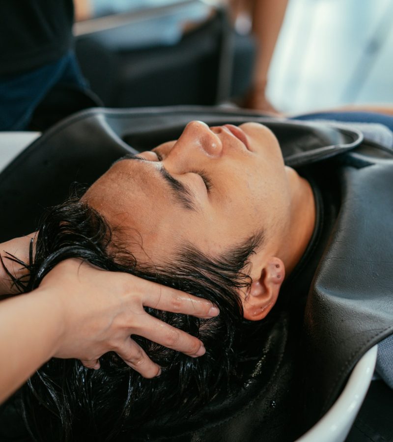 Barber washing head client in barbershop
